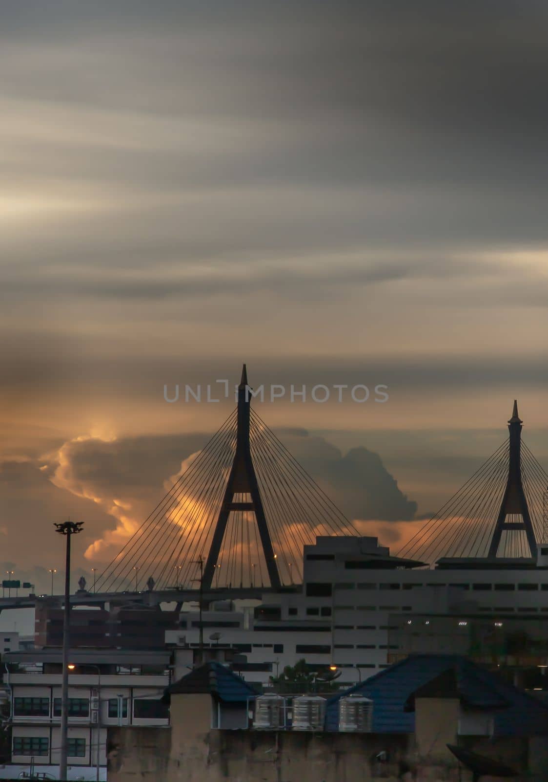 View of Bhumibol suspension bridge cross over Chao Phraya River in Bangkok city at beautiful sunset sky and clouds in Bangkok Thailand. Focus and blur.