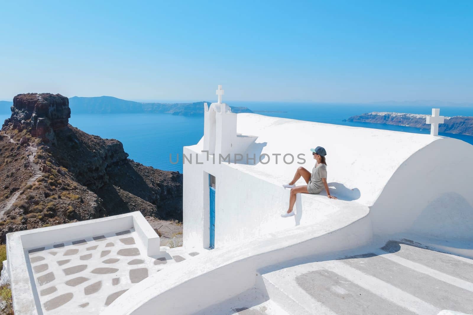 Happy Asian woman visit Oia Santorini Greece on a sunny day during summer with whitewashed homes and churches, Greek Island Aegean Cyclades