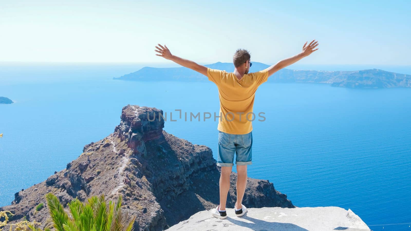 Young men tourists visit Oia Santorini Greece on a sunny day during summer with whitewashed homes and churches, Greek Island Aegean Cyclades