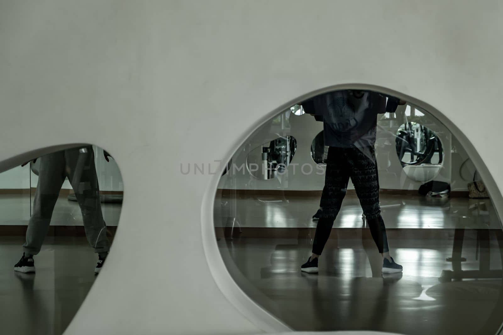 Bangkok, Thailand 11 Oct, 2019 : Young dancer in activewear training in front of large mirror in studio of modern dancing. looking through the glass window. copy space.
