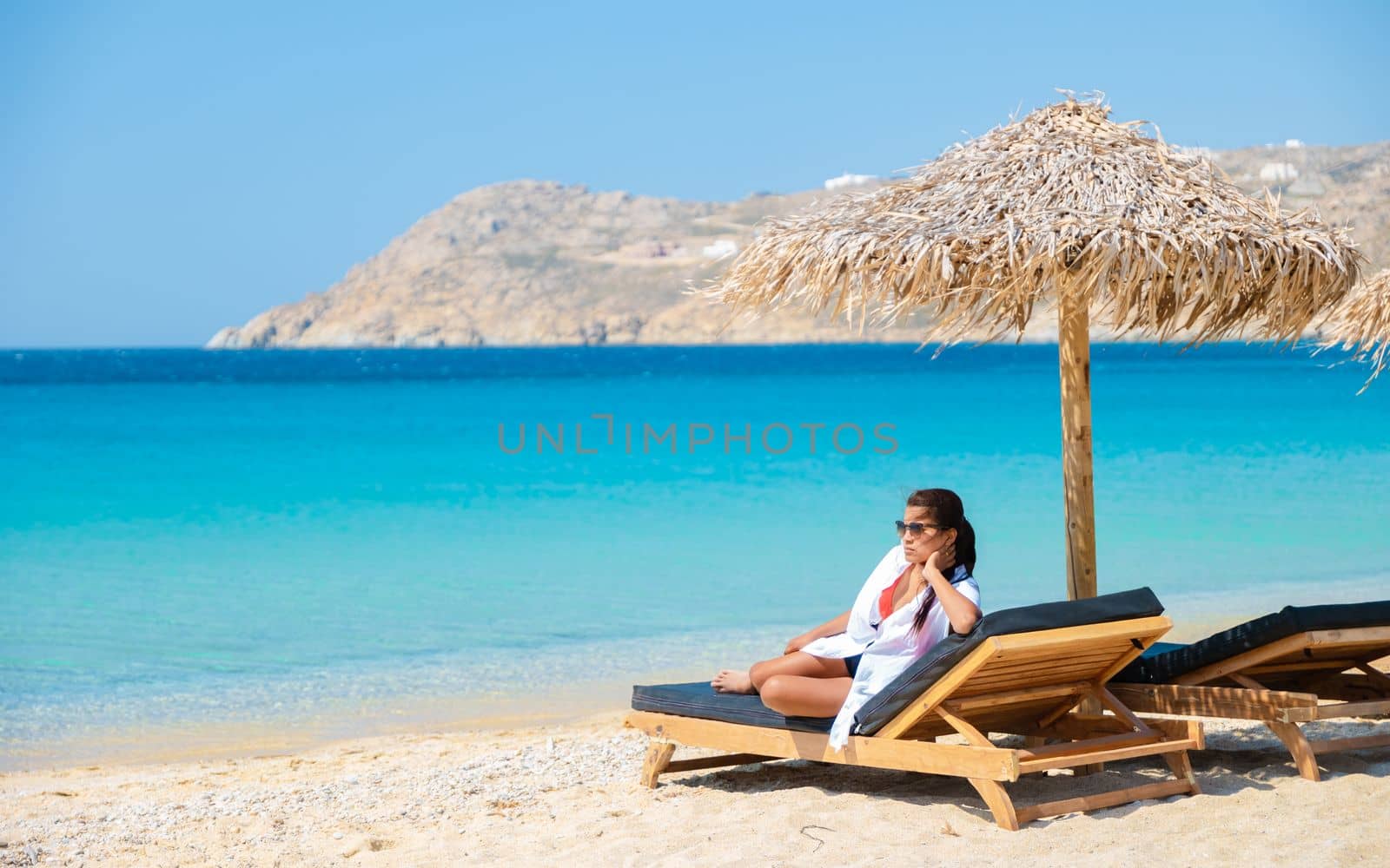 women at Mykonos beach with umbrella and luxury beach chairs at Elia beach Mykonos greece by fokkebok