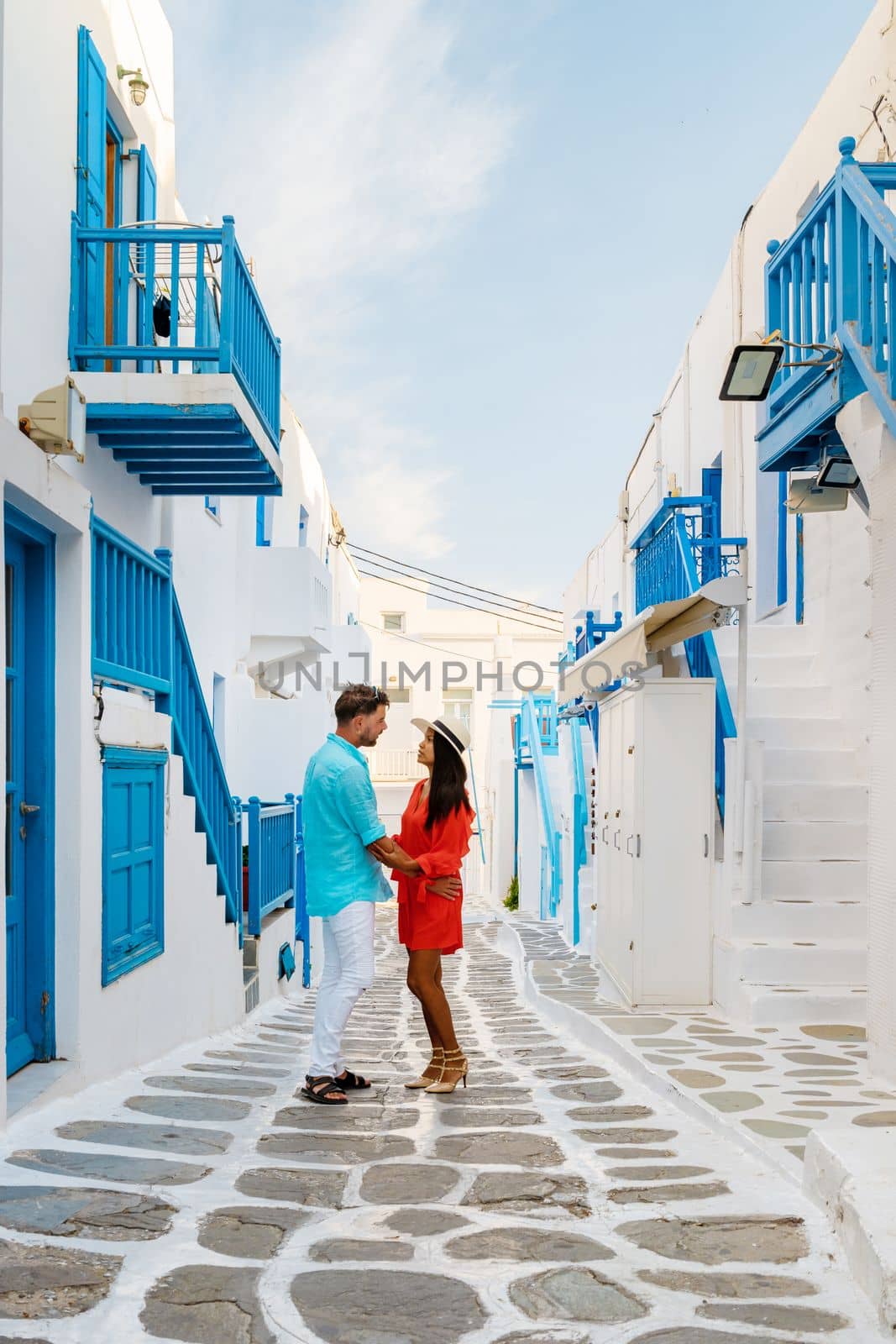 Romantic couple of men and women at the street of Mykonos Greek village in Greece, colorful streets of Mikonos village.in the morning