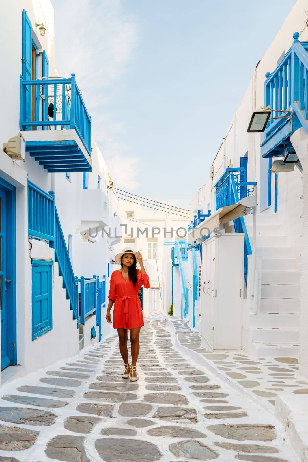 Young women at the street of Mykonos Greek village in Greece, colorful streets of Mikonos village by fokkebok