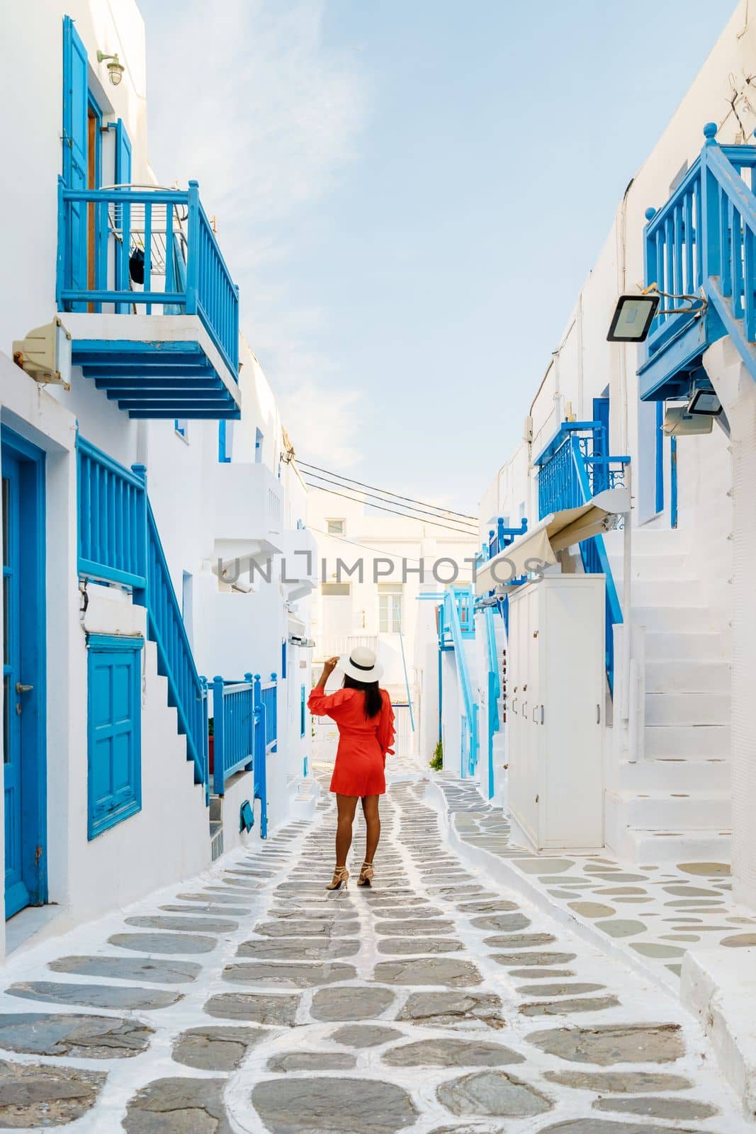 Young women at the street of Mykonos Greek village in Greece, colorful streets of Mikonos village by fokkebok