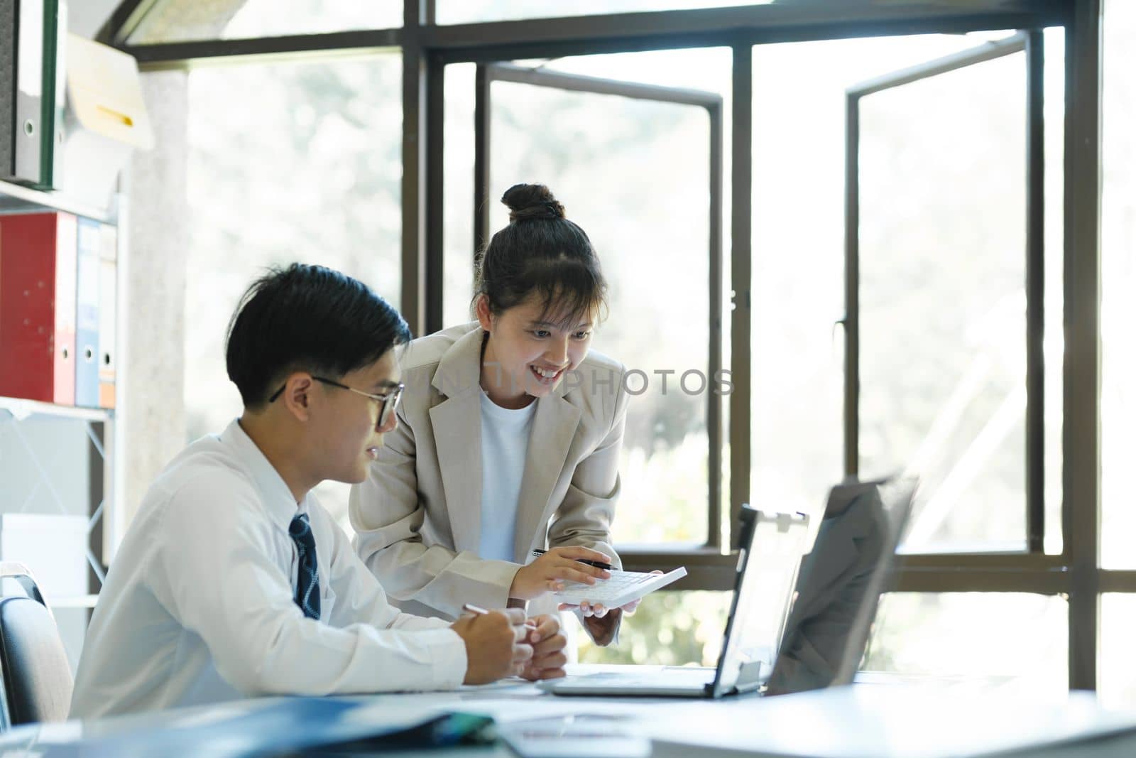 Businesspeople or office workers are working together on investment project. They are discussing, sharing the ideas, planning, and analyzing the business strategy. And set up the budget for financial plan by using laptop and calculator.