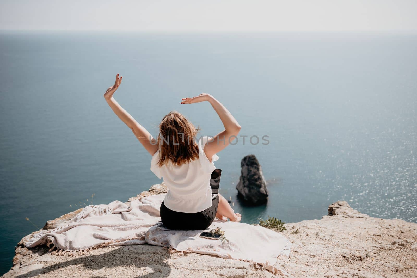 Woman sea laptop. Successful business woman working on laptop by the sea. Pretty lady typing on computer at summer day outdoors. Freelance, digital nomad, travel and holidays concept. by panophotograph