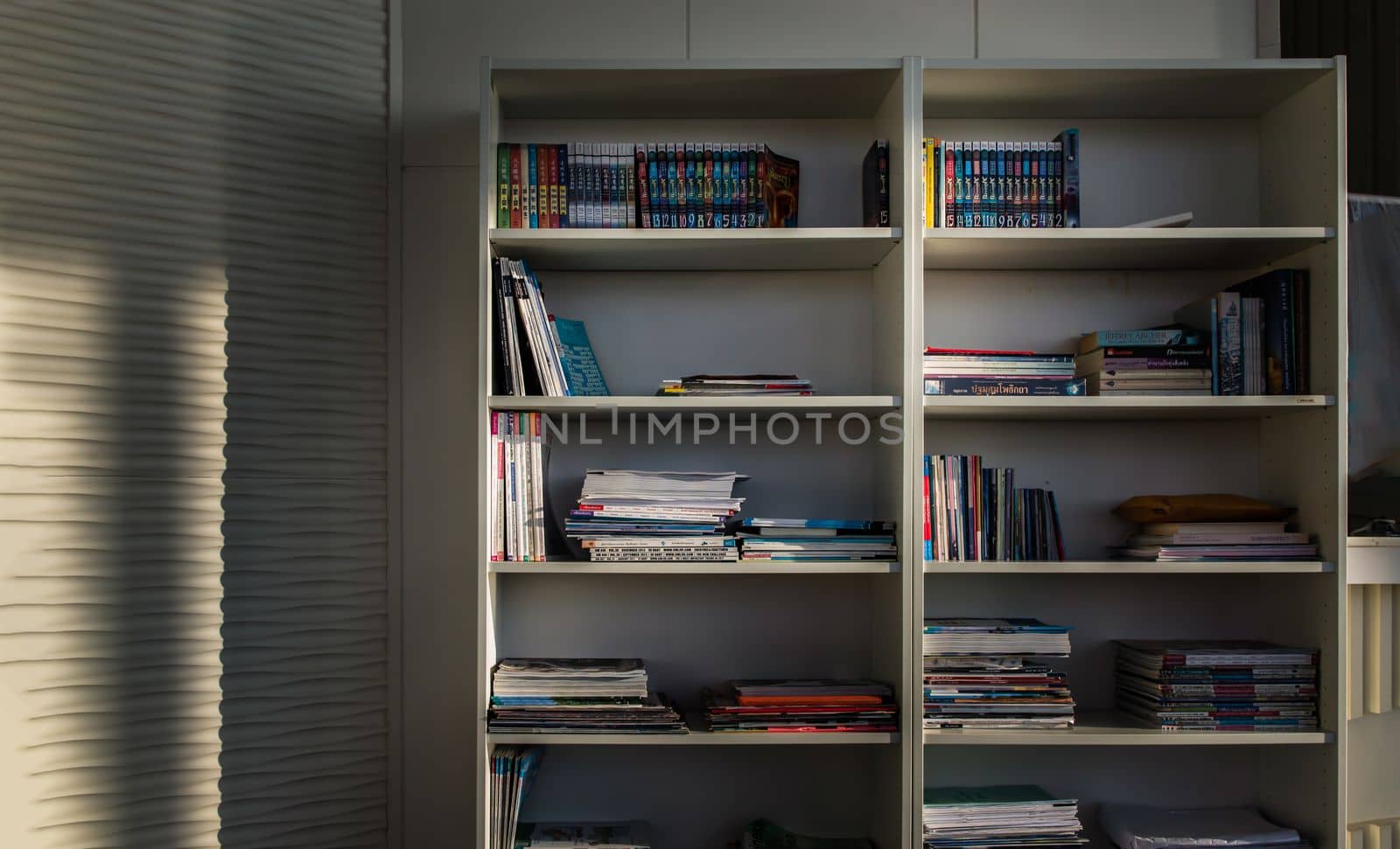 Bangkok,Thailand - Jan 10, 2022 : Library of shared facility at living room of home condominium. Different books are arranged on a white bookshelf, No focus, specifically.