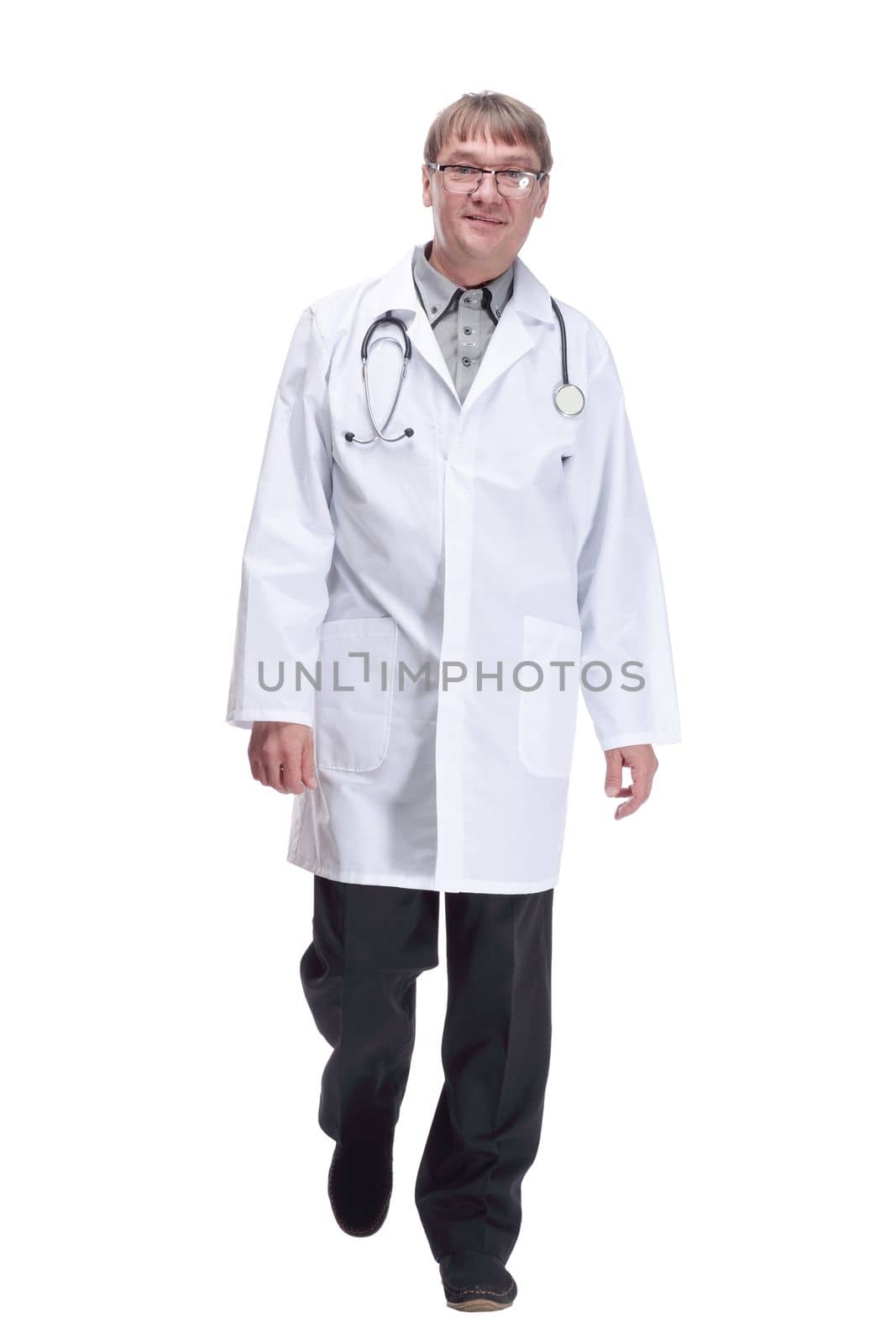 in full growth. friendly doctor with a stethoscope striding forward .isolated on a white background.