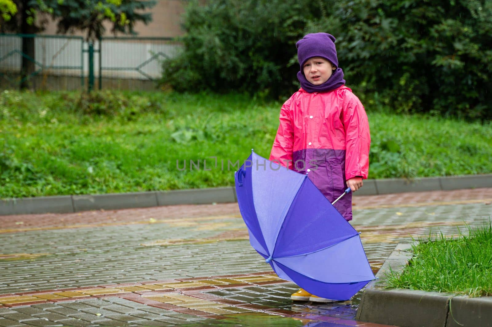 Child with an umbrella walks in the rain. Little boy with umbrella outdoors.