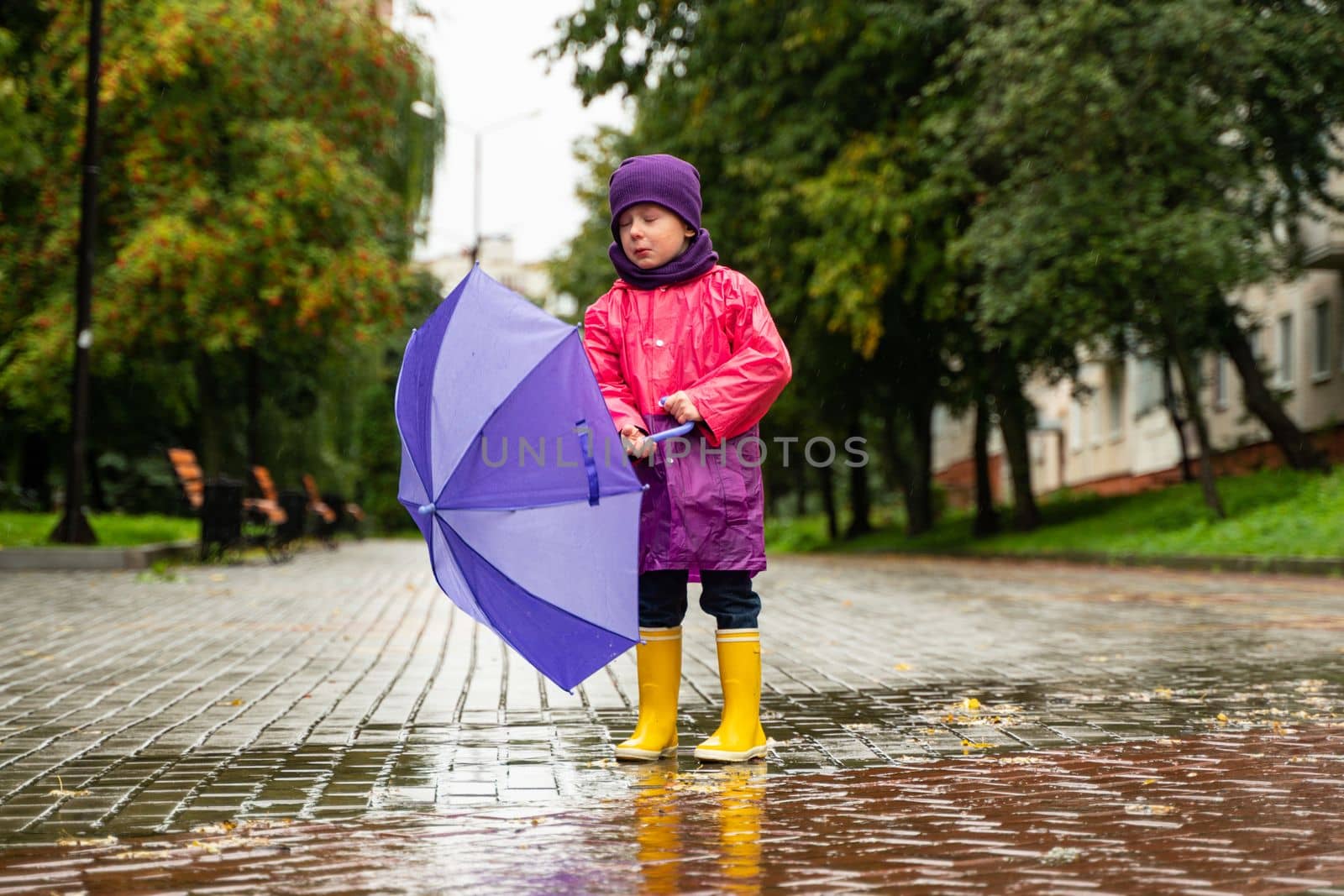 Child playing in autumn rain. Kid with umbrella. Outdoor fun for kids by any weather. Rain waterproof wear, boots and jacket for children by voffka23