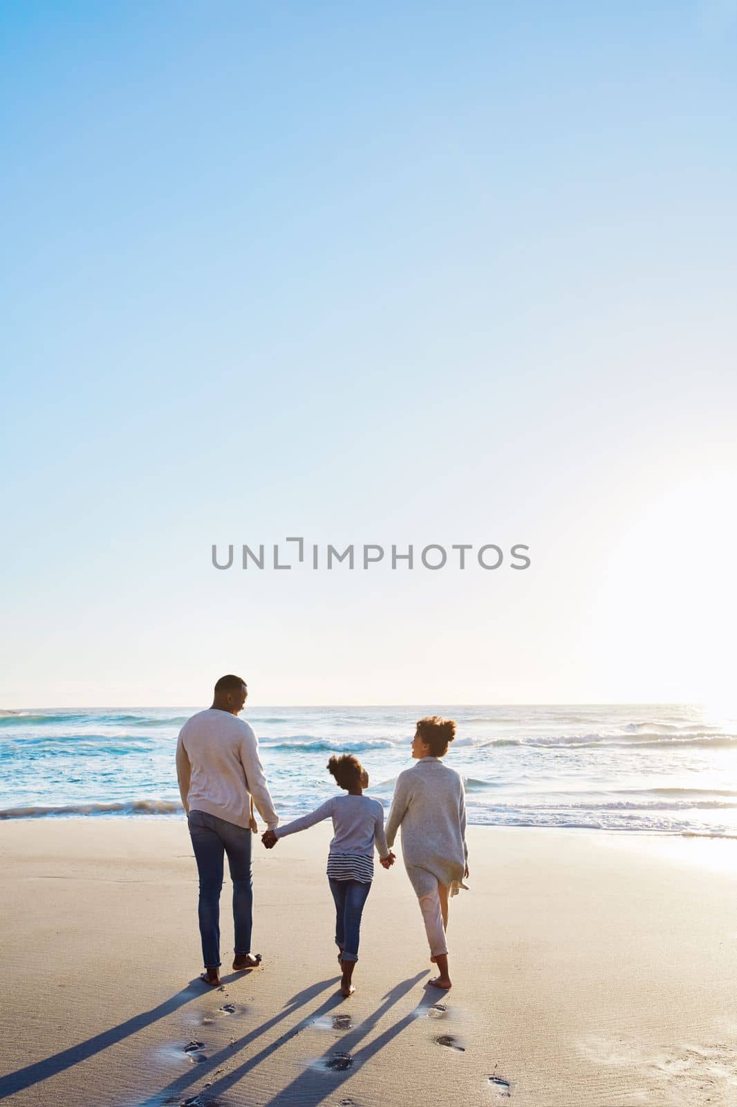 Family, beach and walk during sunset on vacation or holiday relaxing and enjoying peaceful scenery at the ocean. Sea, water and parents with daughter, child or kid with childhood freedom.