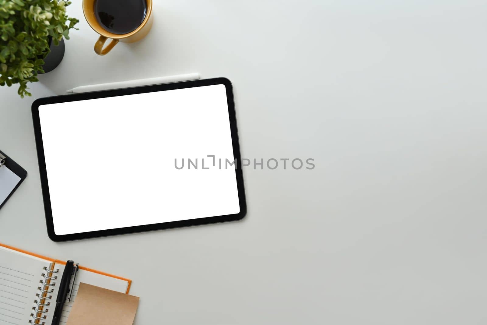 White working desk with digital tablet, notebooks and coffee cup. Blank display for your advertise design by prathanchorruangsak