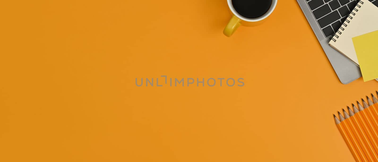 Laptop computer, notepad and coffee cup on yellow background. Copy space for your advertise text.
