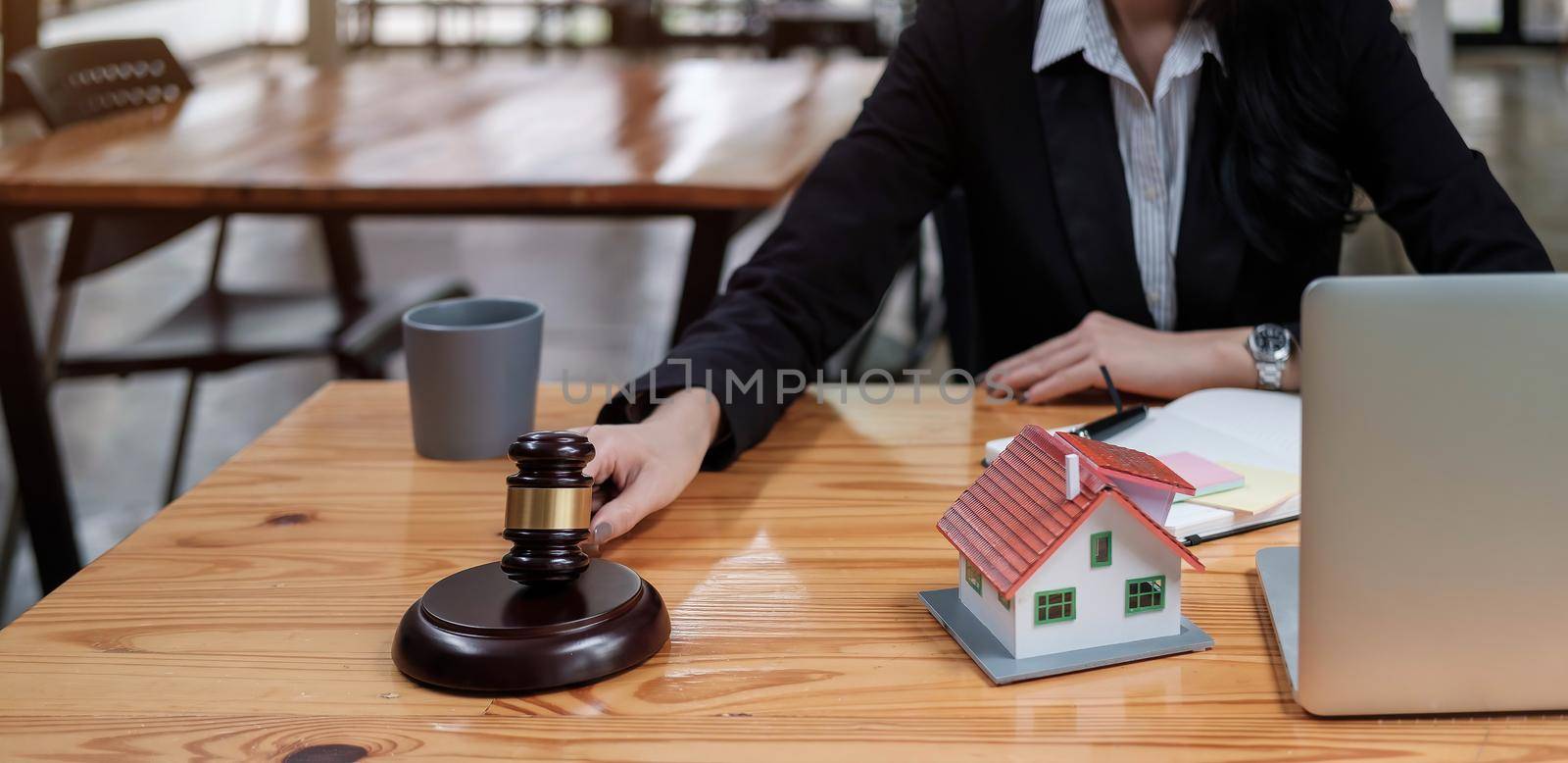 Real Estate Law concept. Gavel on sounding block in hand's female judge at a courtroom, working for the insurance compensations. report the case on table in modern office. by wichayada