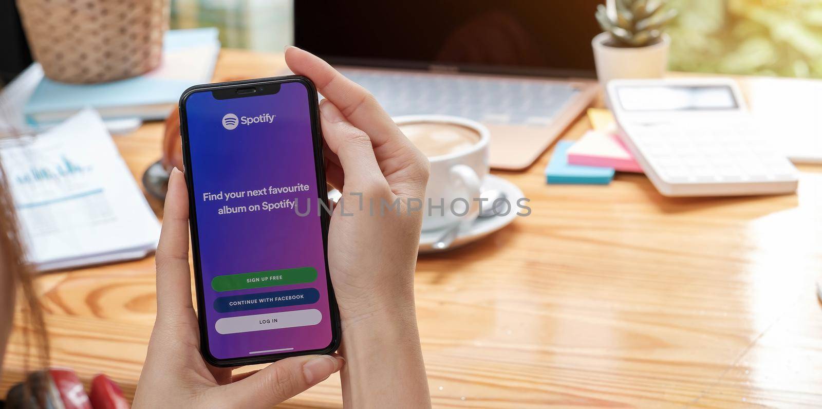 CHIANG MAI, THAILAND - JUL 27 2021: Person holding a brand new Apple iPhone XS with Spotify logo on the screen. Spotify is a popular commercial music streaming service. by wichayada