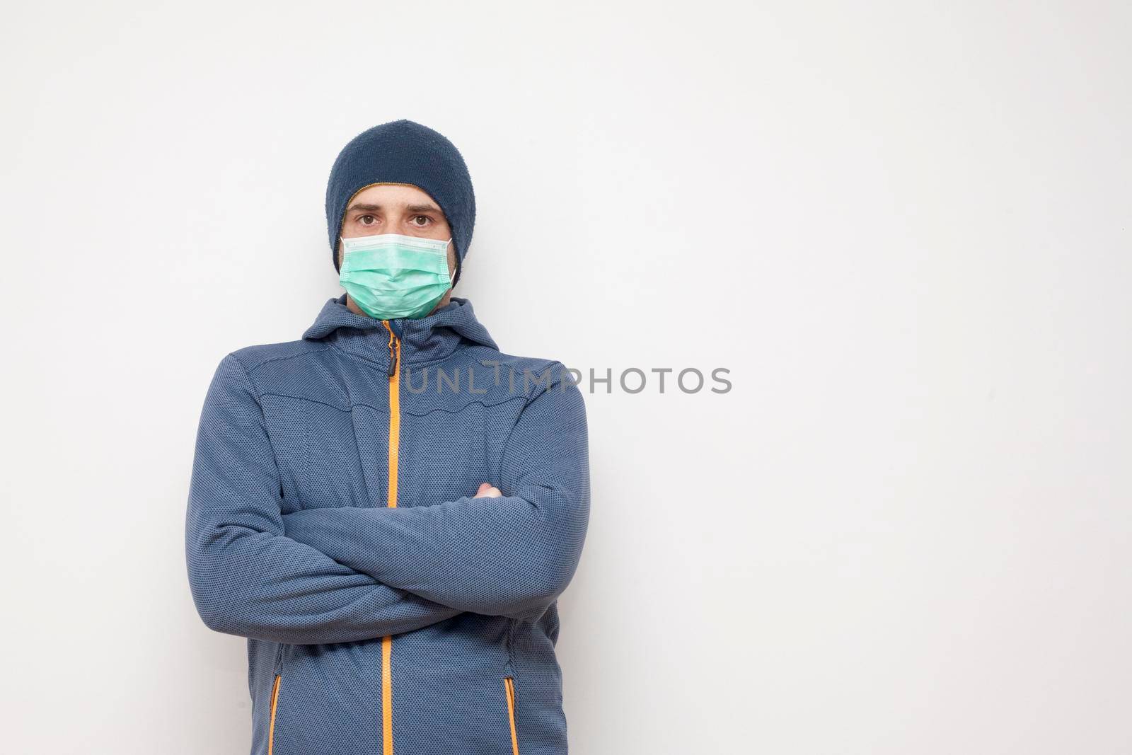 Man with green protective mask on white background. A man with a blue jacket, with a hood.