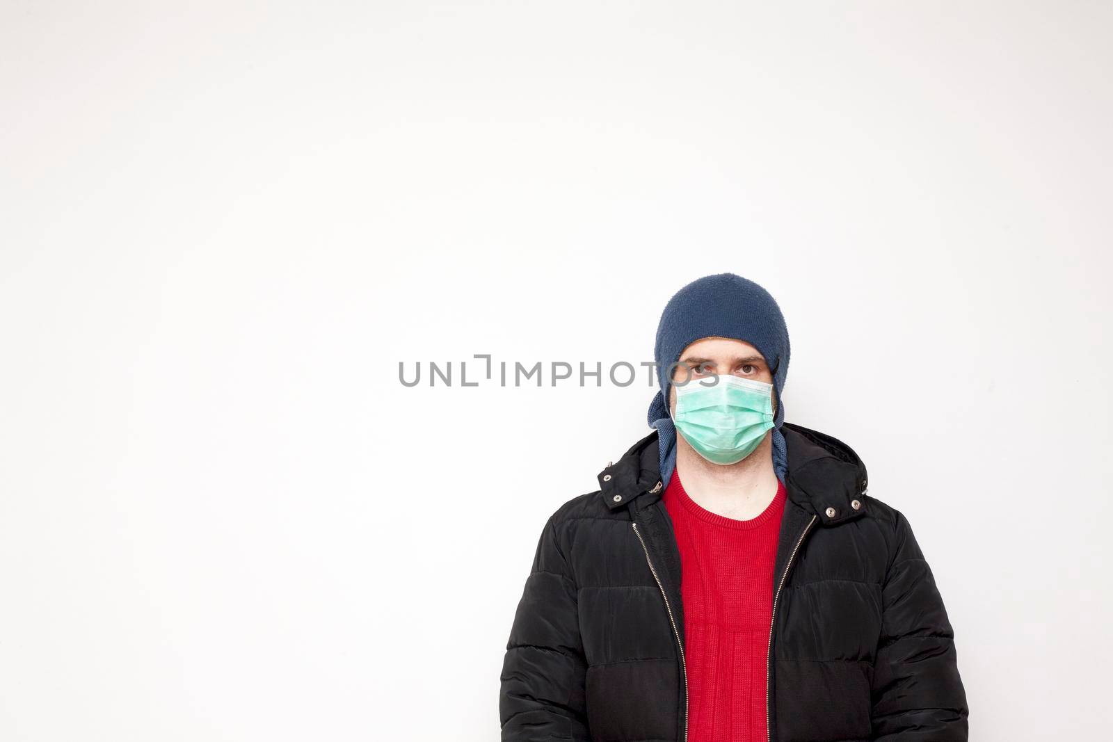 Man with green protective mask on white background. A man with a red sweater and a black jacket.