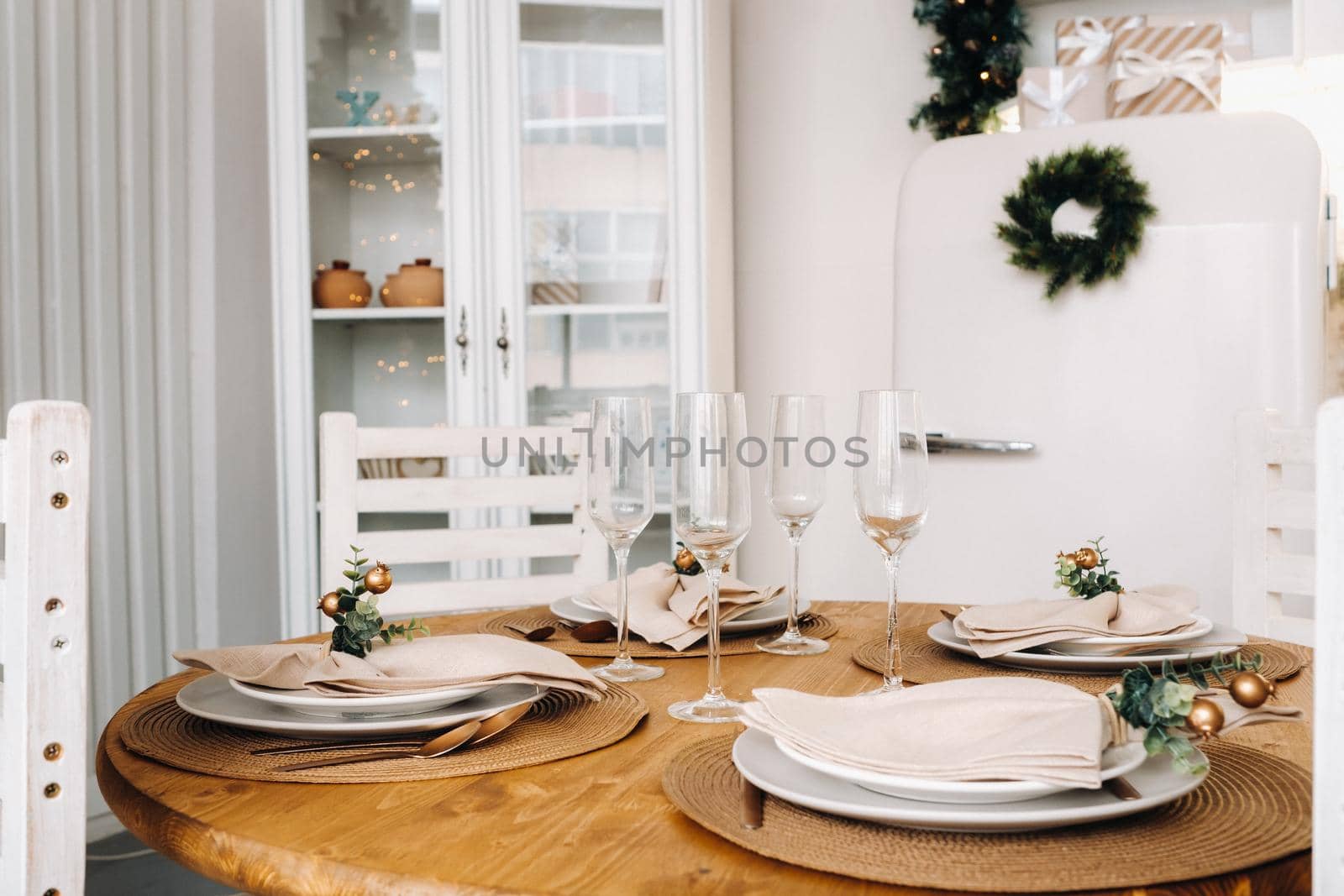 Christmas table decoration in the kitchen, Banquet table with glasses before serving food, close-up of the Christmas dinner table with seasonal decorations, crystal glasses and decorative deer by Lobachad