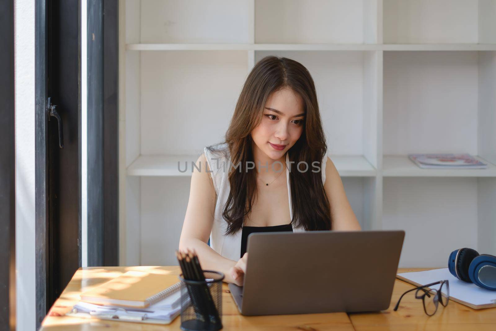 Asian Business woman sitting in office with laptop computer on wooden desk