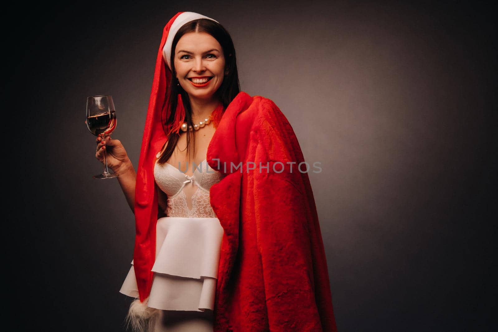 a woman in a Christmas hat and white dress, holding a glass and a red fur coat in her hands, on a black background, Christmas, holiday by Lobachad