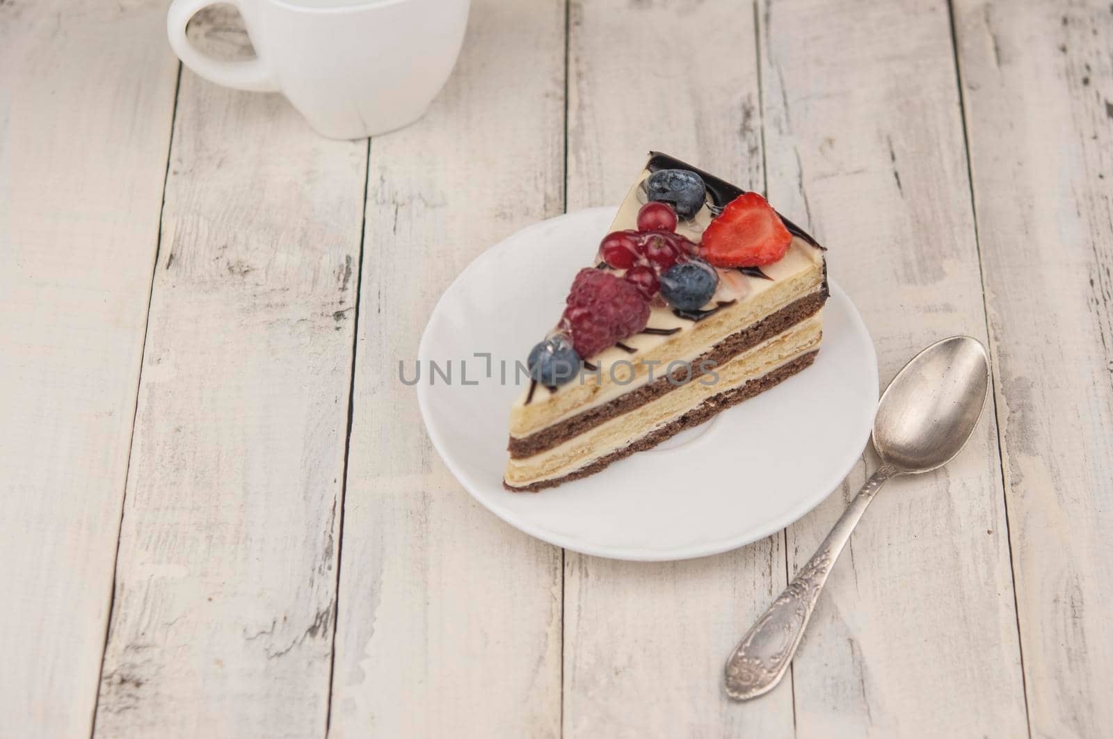 Mix berry colorful slice cake on white plate on wood background