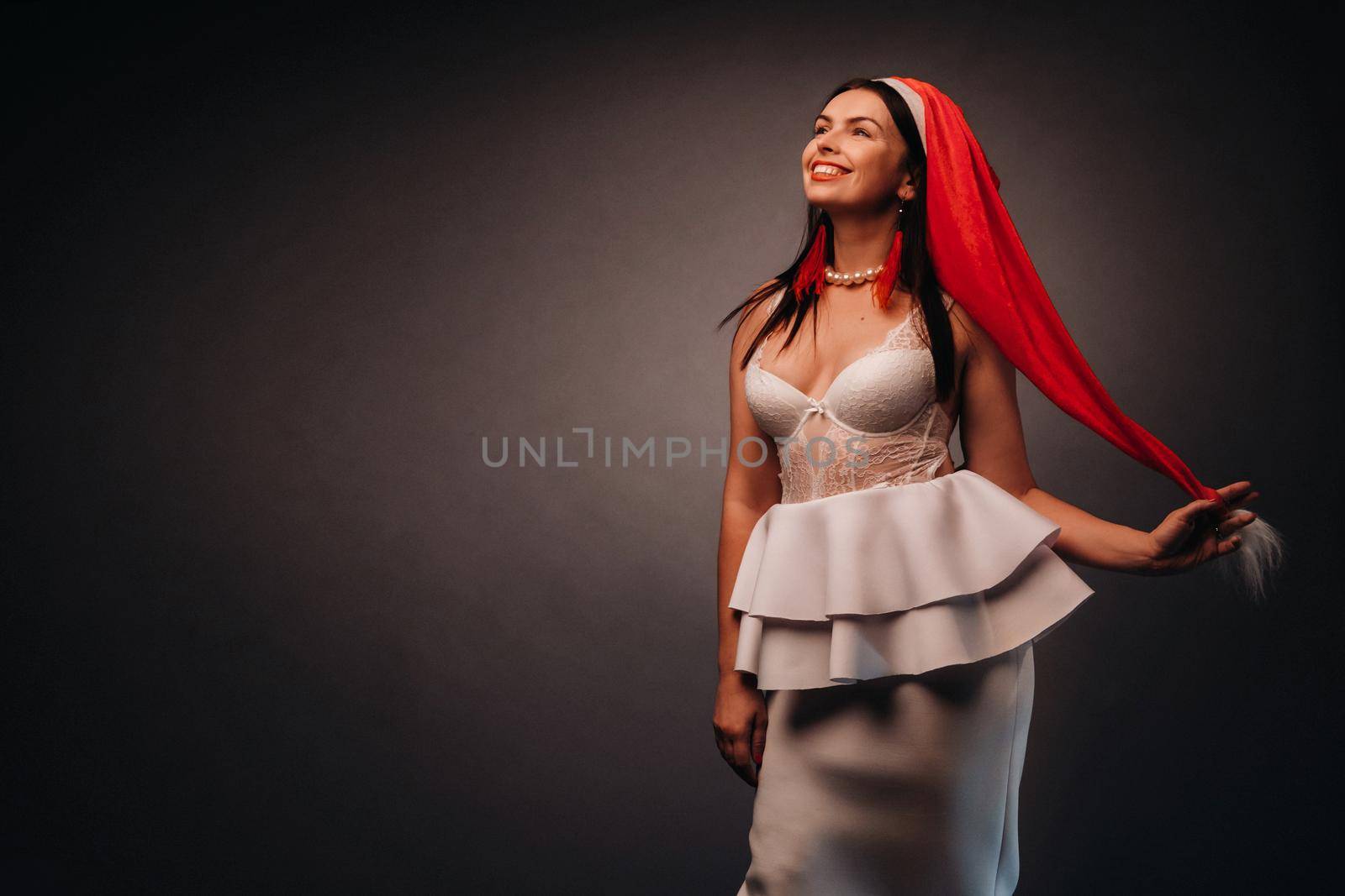 woman in Christmas hat and white dress on black background Christmas, holiday.