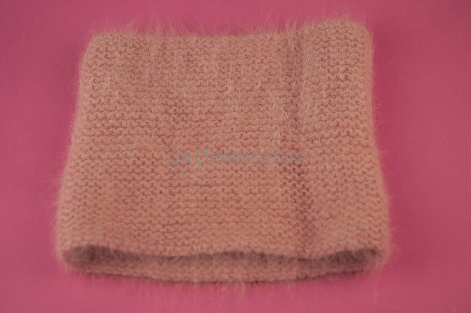 Woman winter knitted scarf front on pink background.