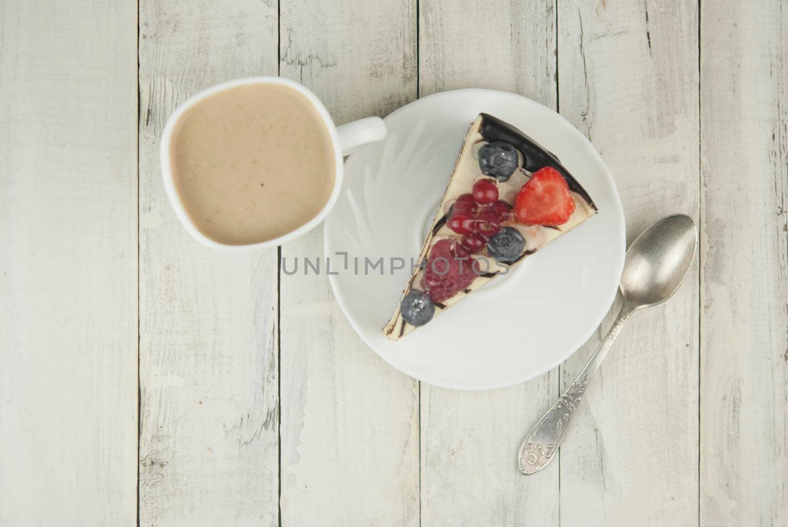 Mix berry colorful slice cake on white plate on wood background