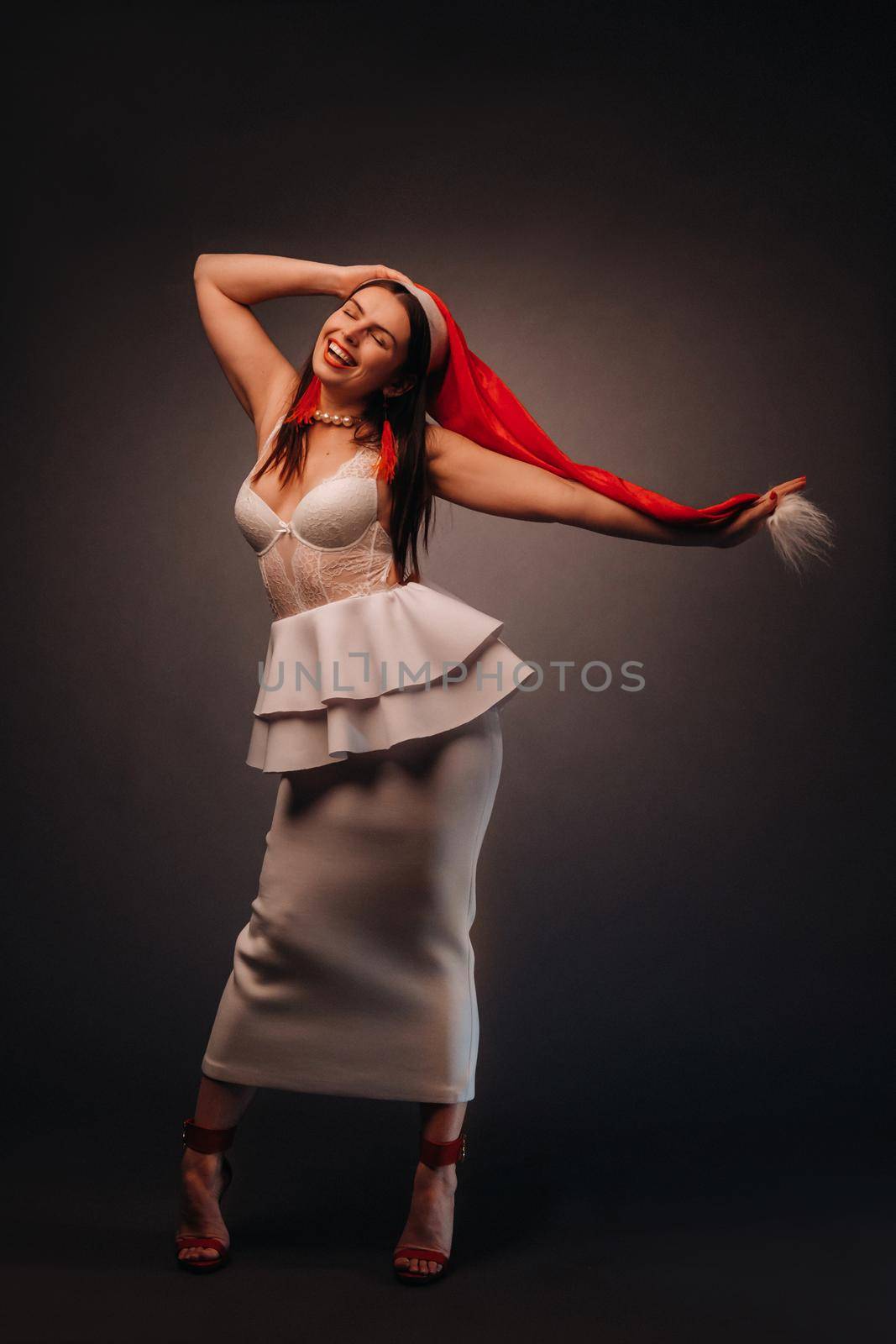 woman in Christmas hat and white dress on black background Christmas, holiday.