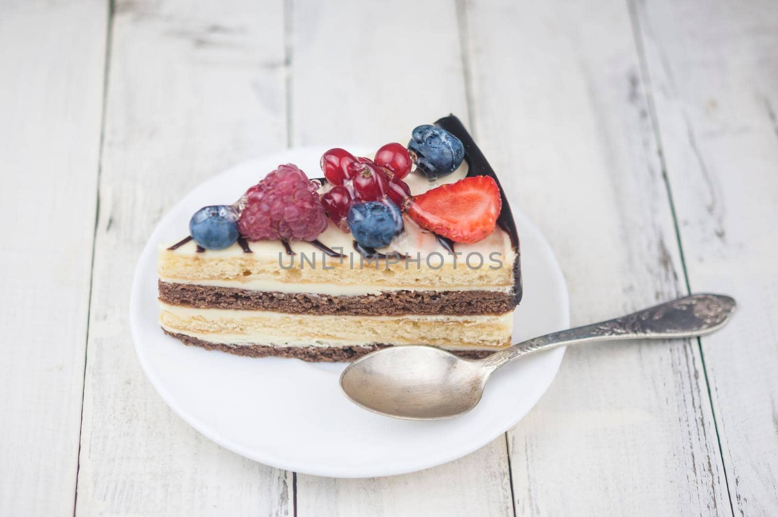Mix berry slice cake on white plate on wood background