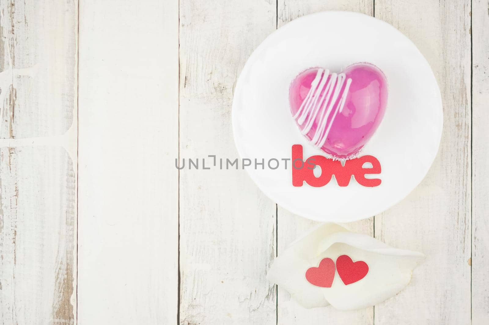 word love and white petals rose with red cake in the shape of a heart is on the table. Romantic date. 