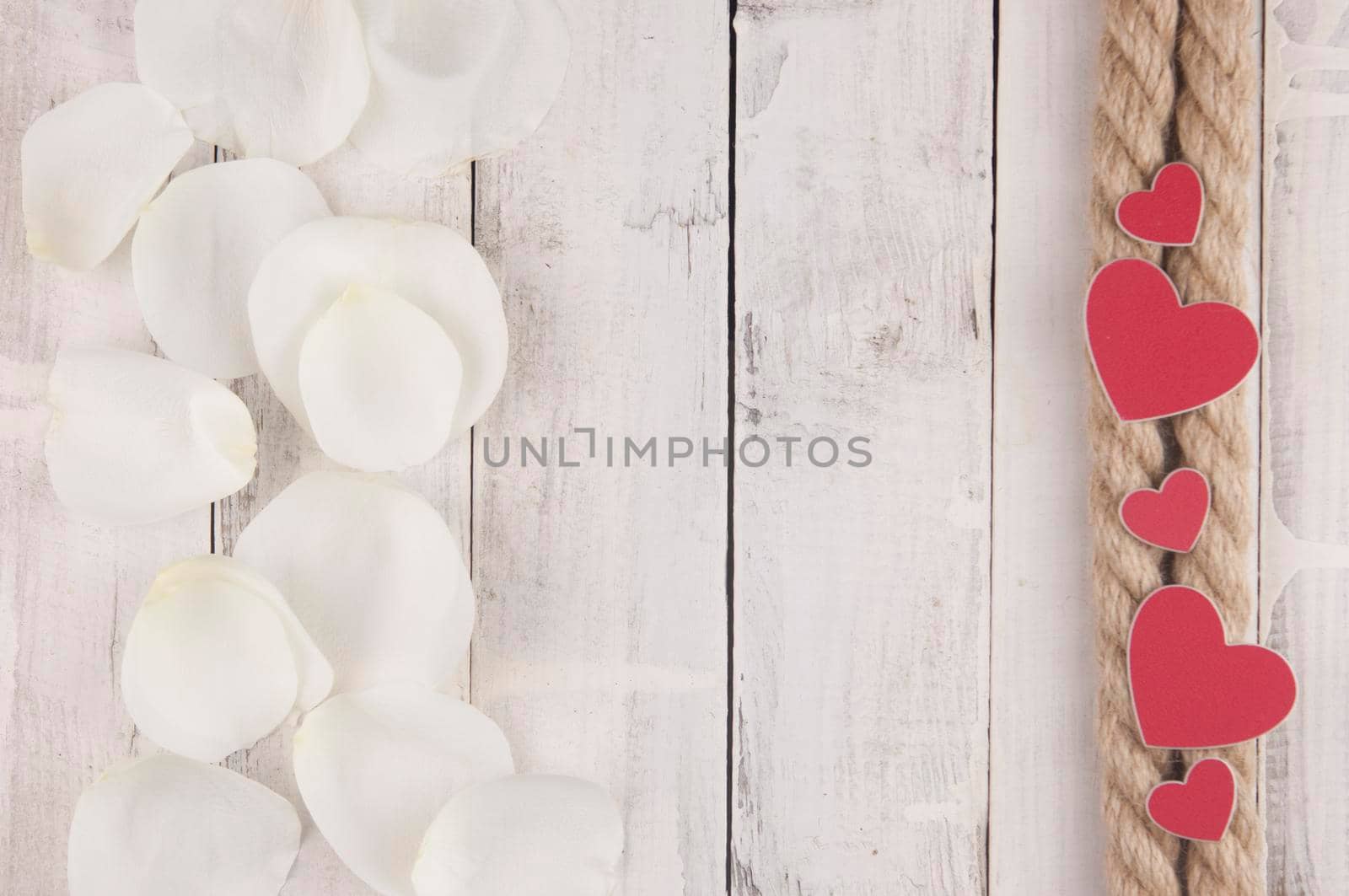 hemp rope wyth red hearts and white rose petals on the white wood table. Romantic date. breakfast. Birthday. Wedding. Holiday. Top view. Copy space