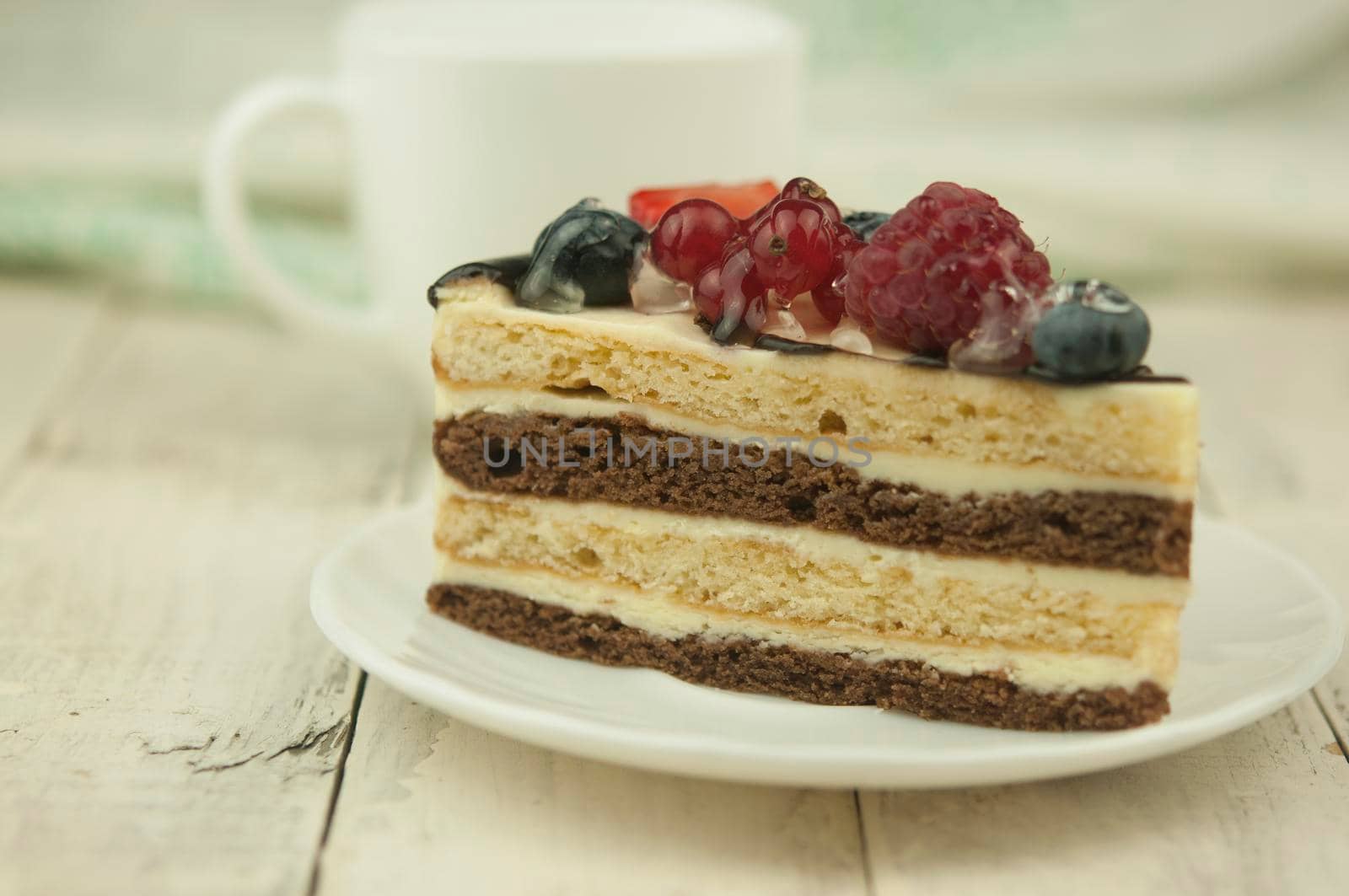 Mix berry colorful slice cake on white plate on wood background