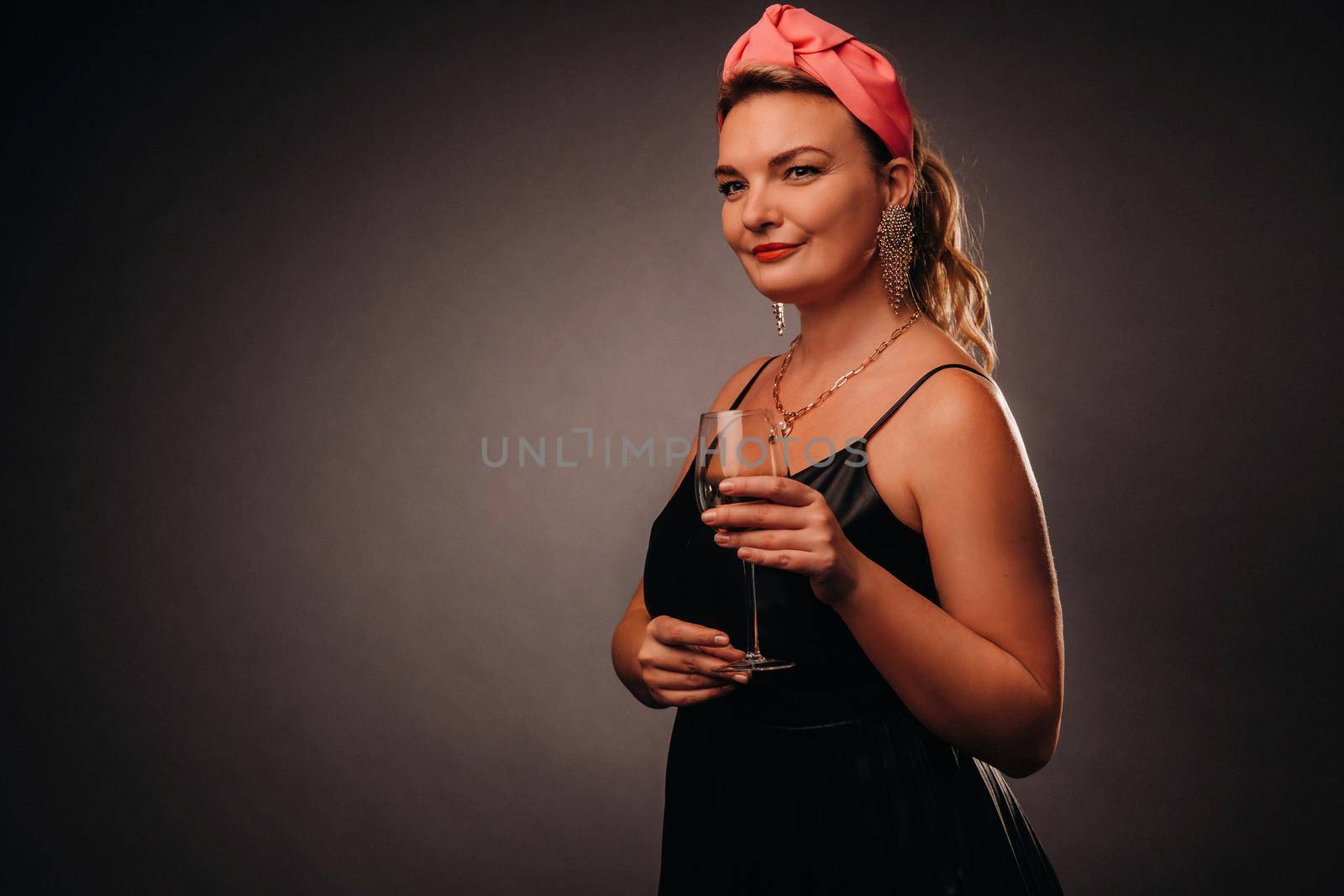 a woman in a black dress holding a glass of champagne on a black background, Christmas, holiday.