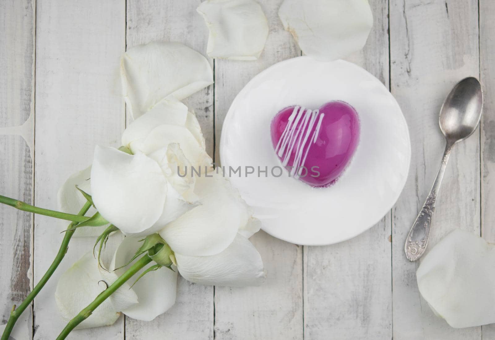 white petals rose with red cake in the shape of a heart is on the table. Romantic date. 