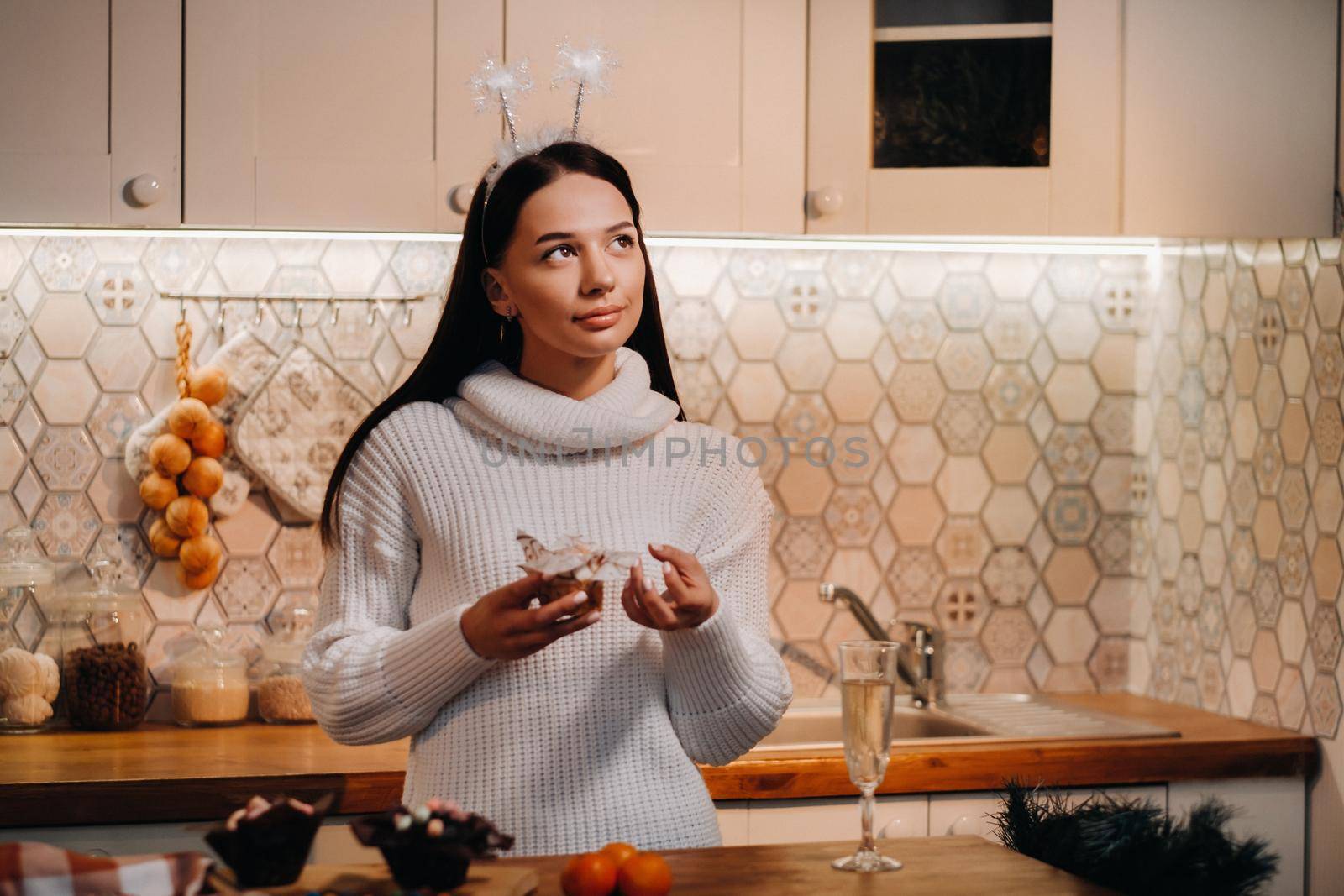 A girl at Christmas stands in the kitchen and holds a cake in her hands and dreams.Woman on new year's eve in the kitchen.