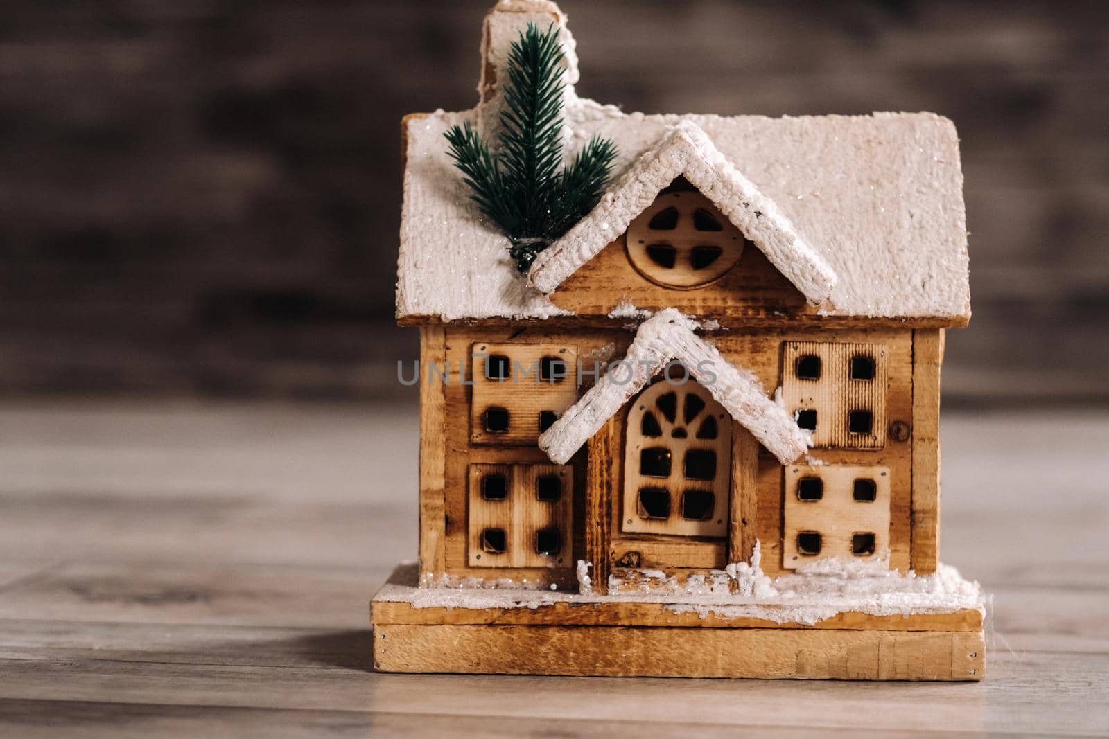 small snow-covered Christmas house on the floor of the house.Winter house decorative by Lobachad