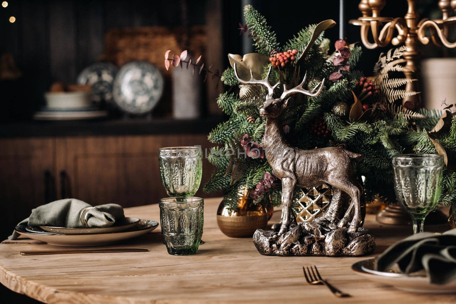 Christmas table decoration, Banquet table with glasses before serving food, Close-up of Christmas dinner table with seasonal decorations, crystal glasses and decorative deer.