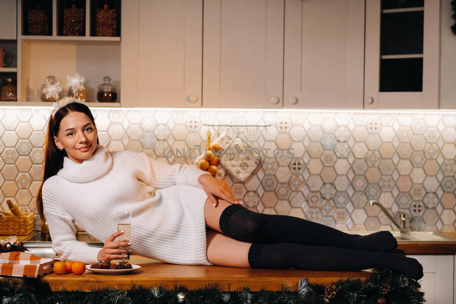 A girl at Christmas is lying on the kitchen table and holding a glass of champagne.Woman on new year's eve with champagne by Lobachad