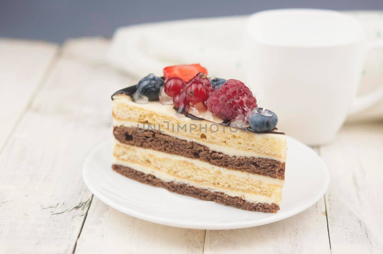 Mix berry colorful slice cake on white plate on wood background