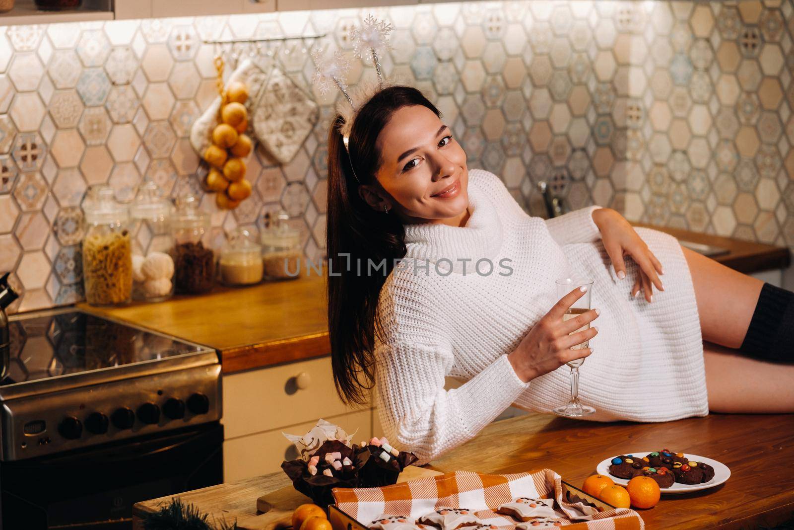 A girl at Christmas is lying on the kitchen table and holding a glass of champagne.Woman on new year's eve with champagne.