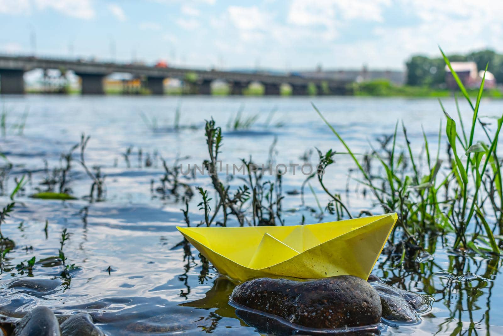 A paper boat shipwreck near a rocky river bank. Conceptual photo showing potential hazards in maritime transport