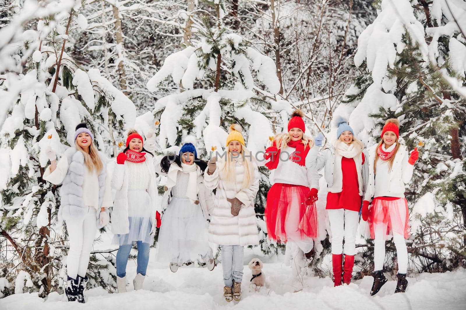 A large group of girls with lollipops in their hands stands in the winter forest.Girls in red and white clothes with candy in a snow-covered forest. by Lobachad