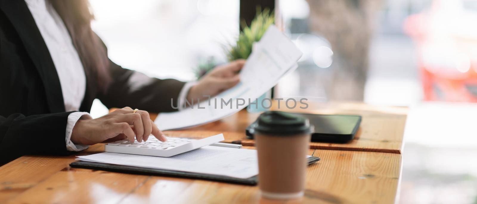 accountant working on desk using calculator for calculate finance report in cafe shop