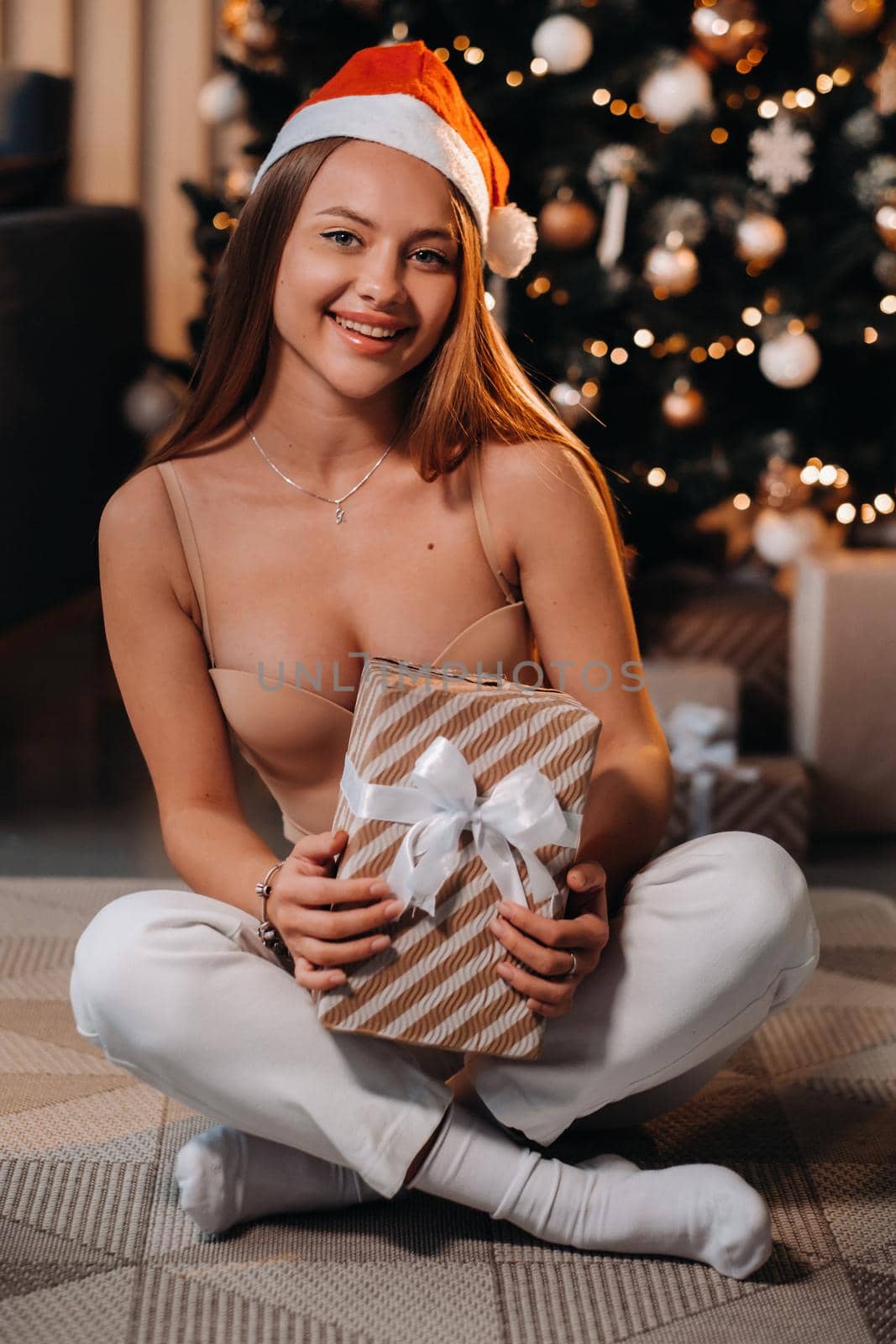 A girl with a toy in her hands stands at home near the Christmas tree.