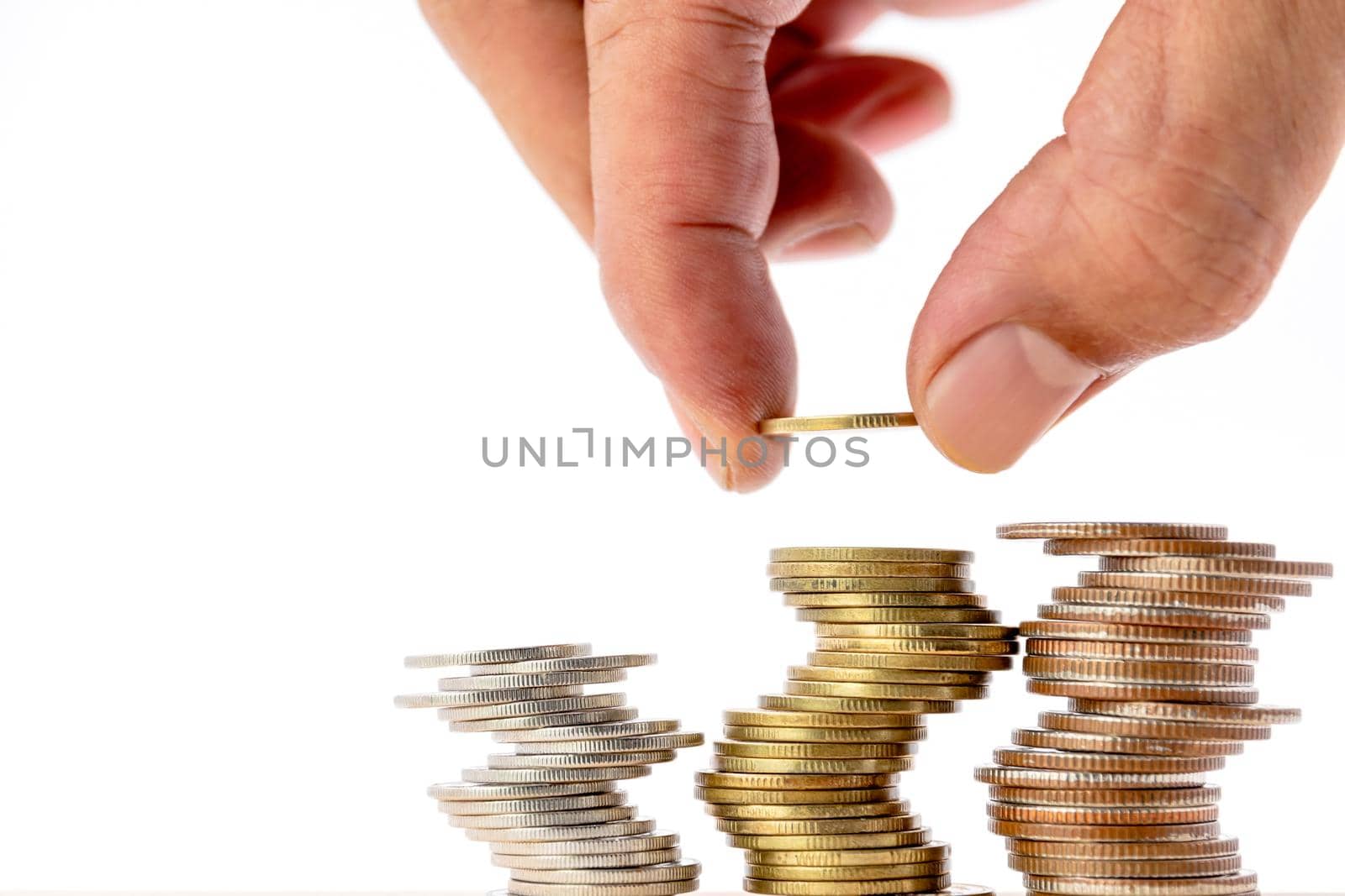 Closeup of human hand putting a coin on a pile of coins, use for business and finance concepts.