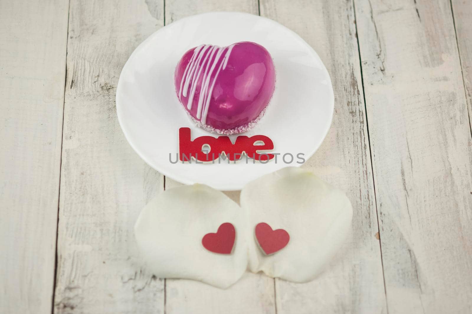 word love and white petals rose with red cake in the shape of a heart is on the table. Romantic date. 