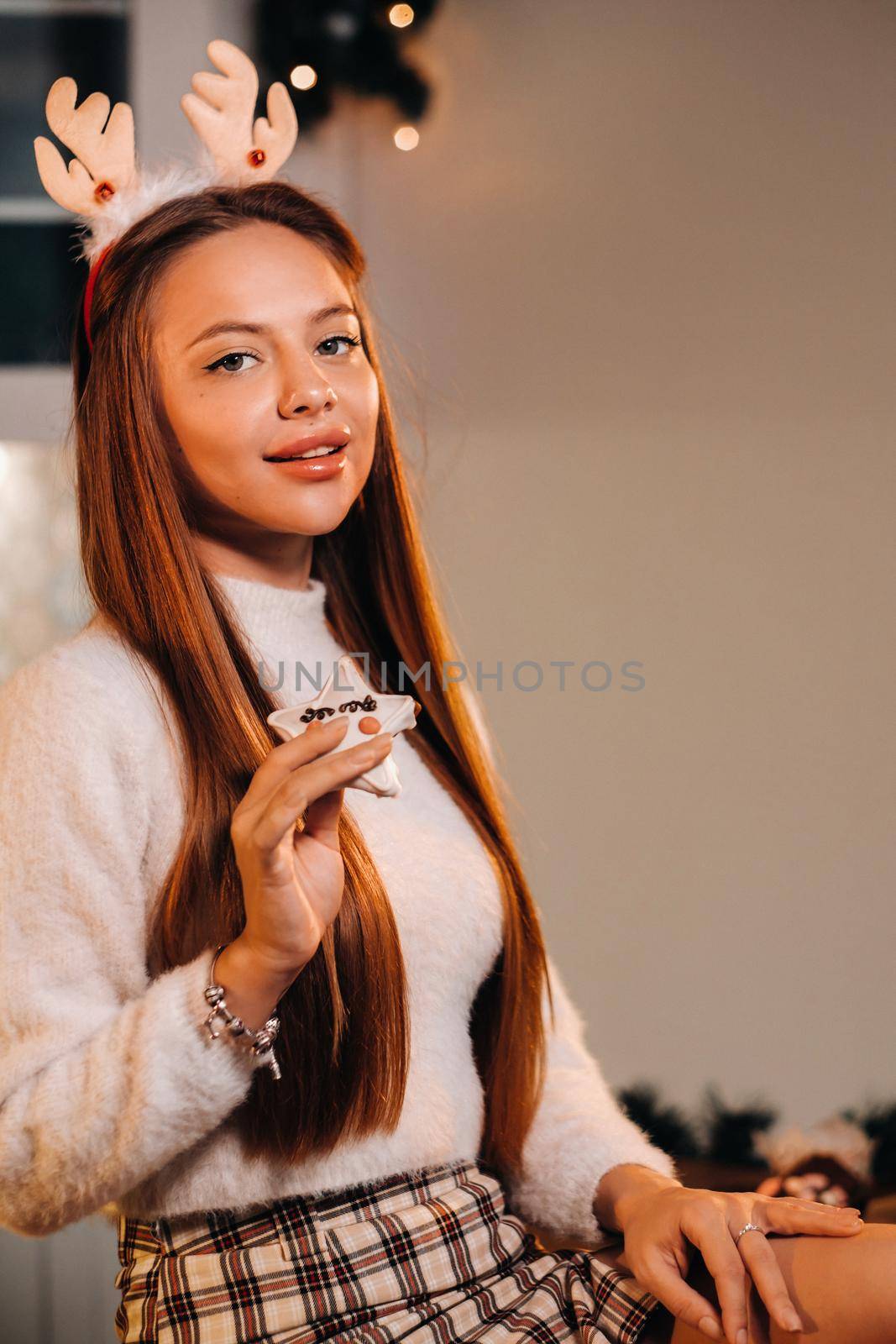 A girl at Christmas holds a cookie in her hands and smiles.Woman on new year's eve in the kitchen