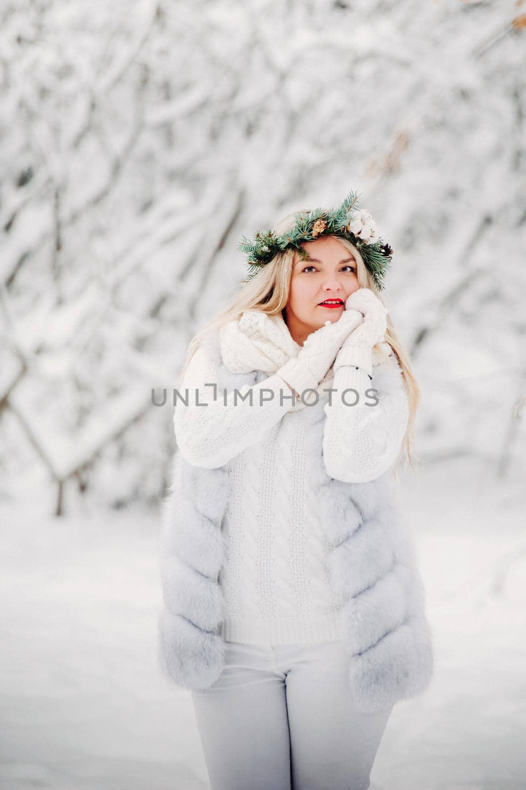 PPortrait of a woman in white clothes in a cold winter forest. Girl with a wreath on her head in a snow-covered winter forest.