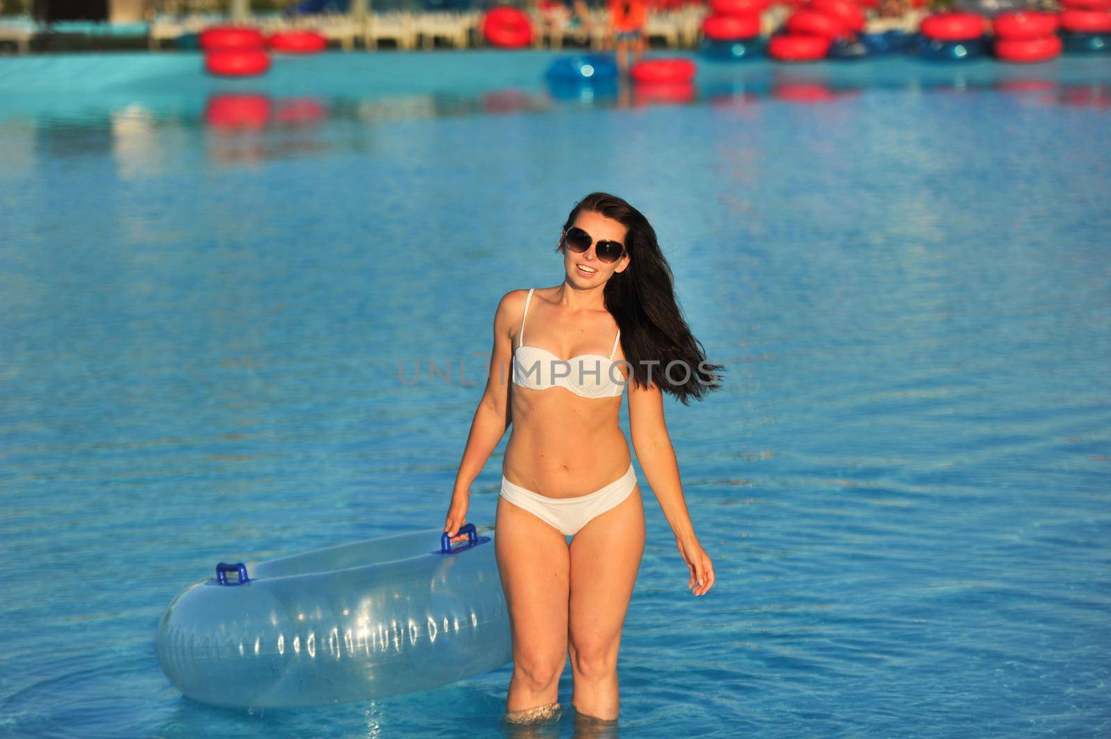 A woman in a white bathing suit with an inflatable circle in a water Park.